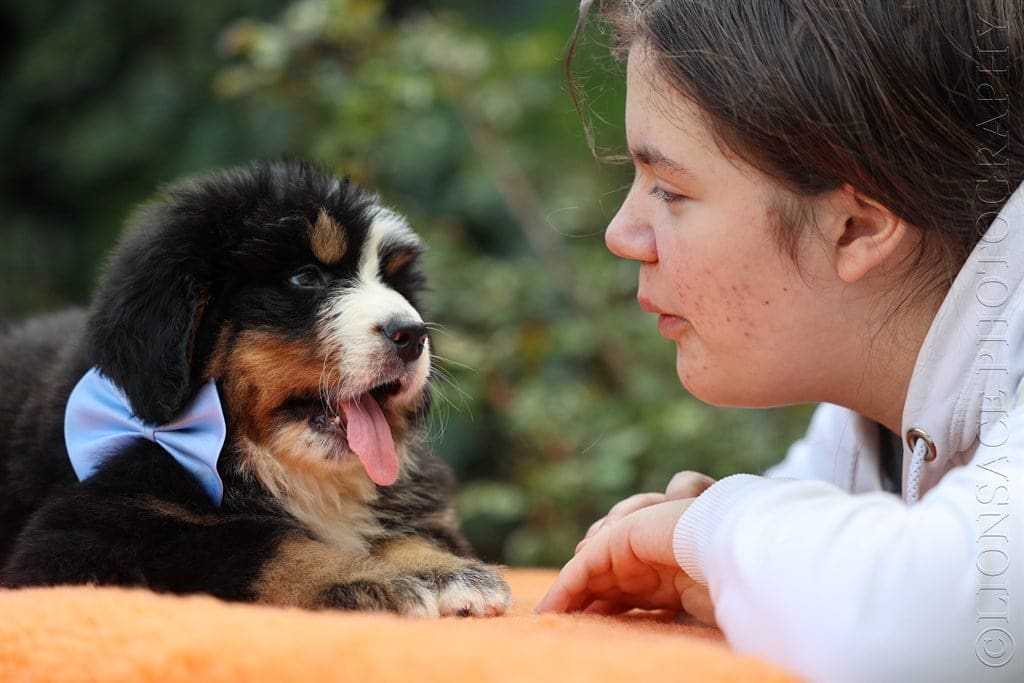 A woman is petting her dog while wearing a tie.